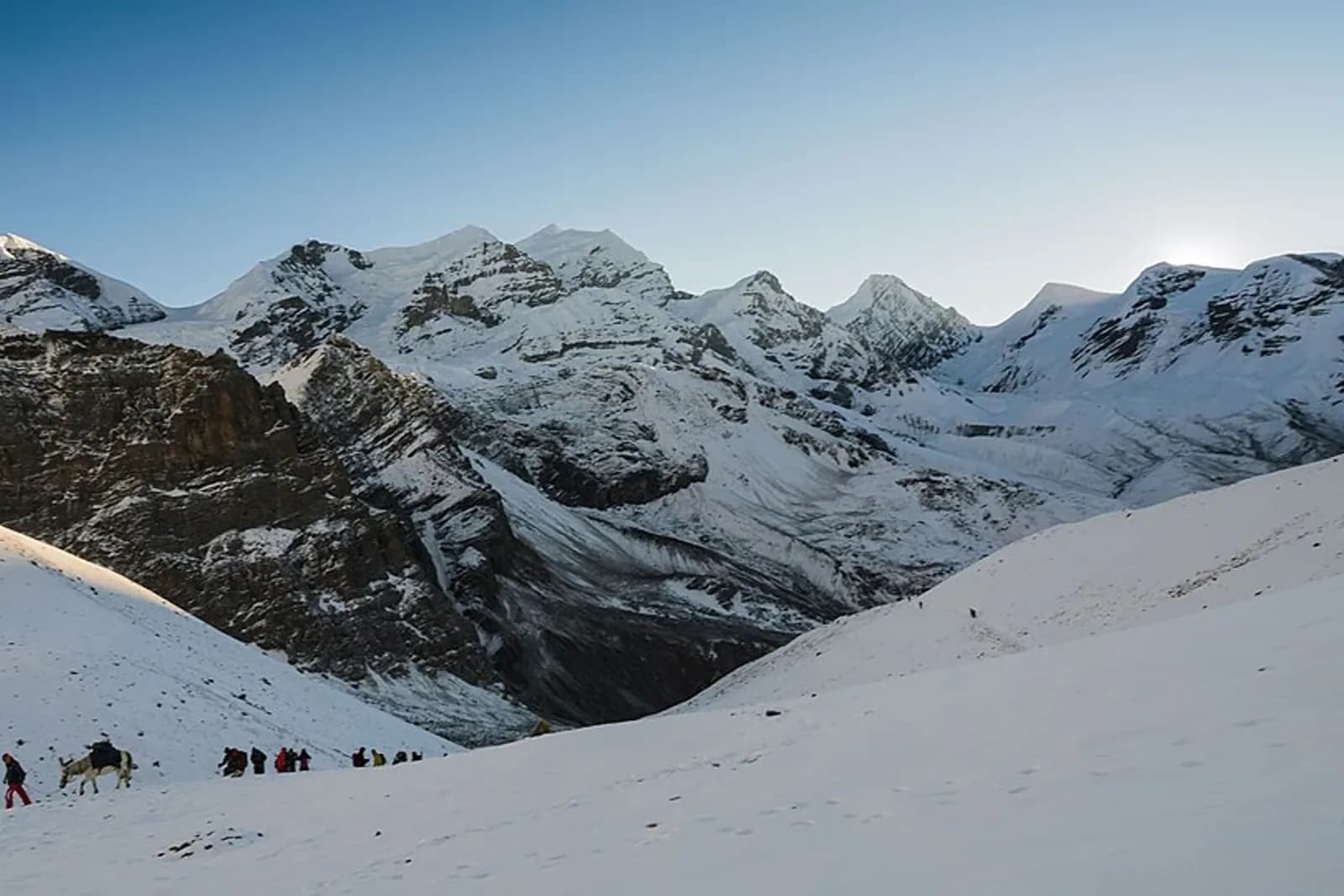 Trekkers climbing up towards Thorung La pass with the morning sunrise.